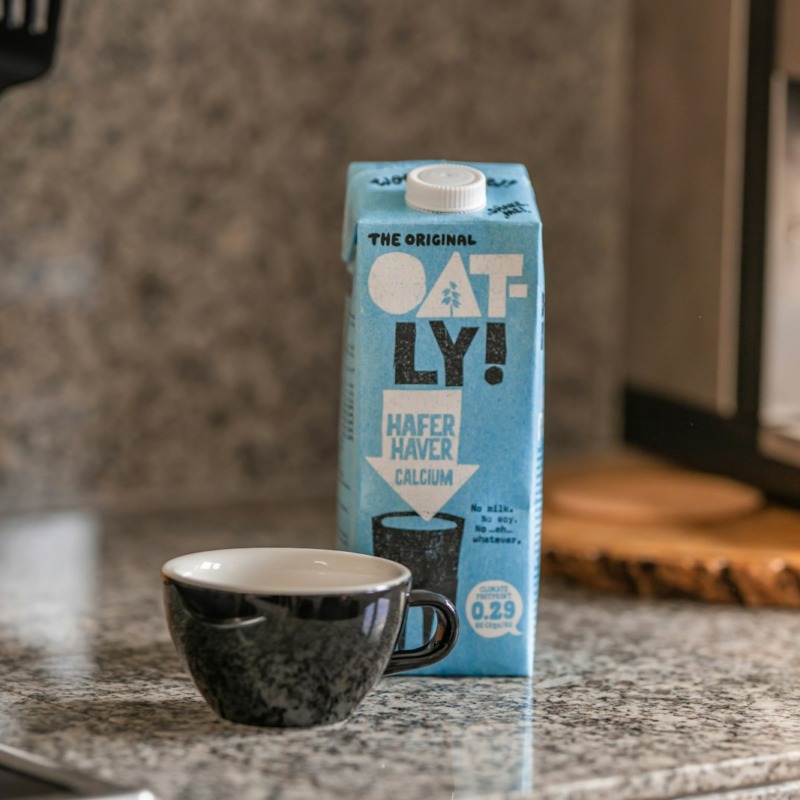 Mermer tezgahta Oatly yulaf sütü kartonu ve espresso fincanı