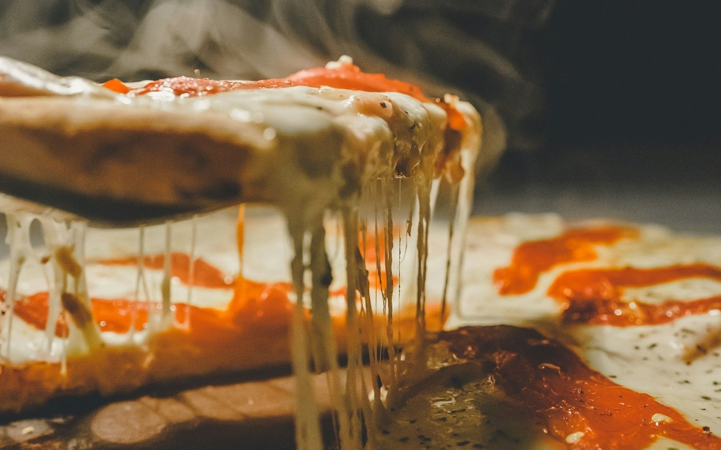 Fırından yeni çıkmış pizza diliminde erimiş mozzarellanın uzaması